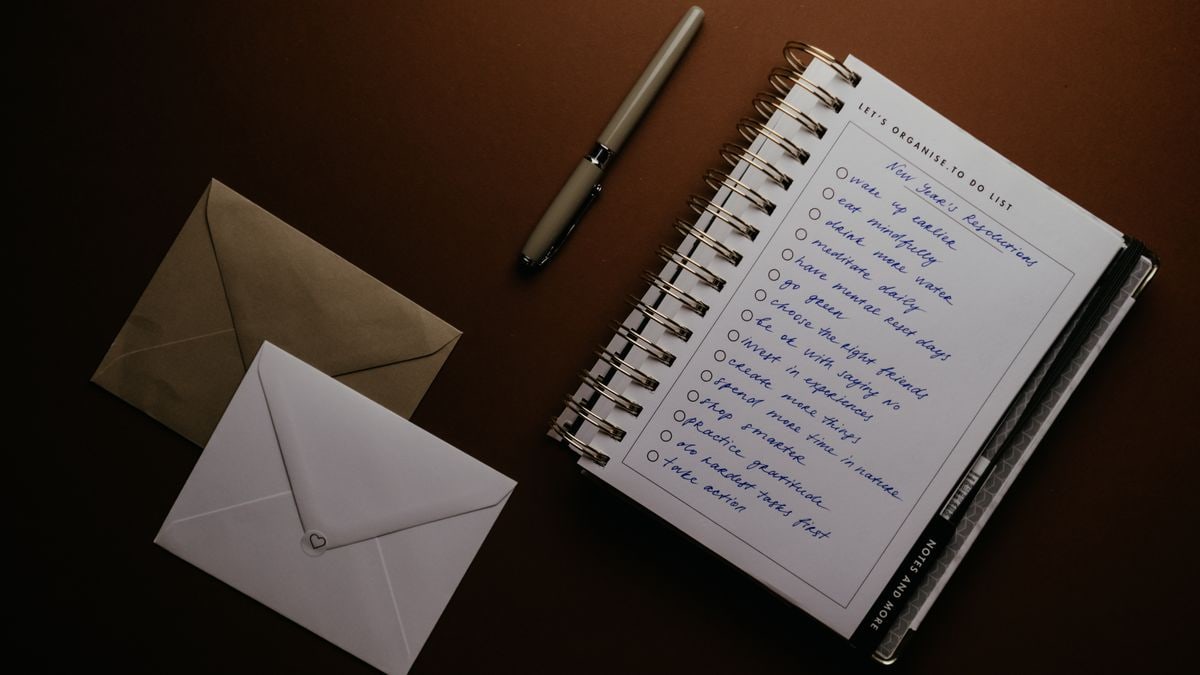 Flat lay of a to-do list, pen, and envelopes on a brown surface, ideal for planning themes.